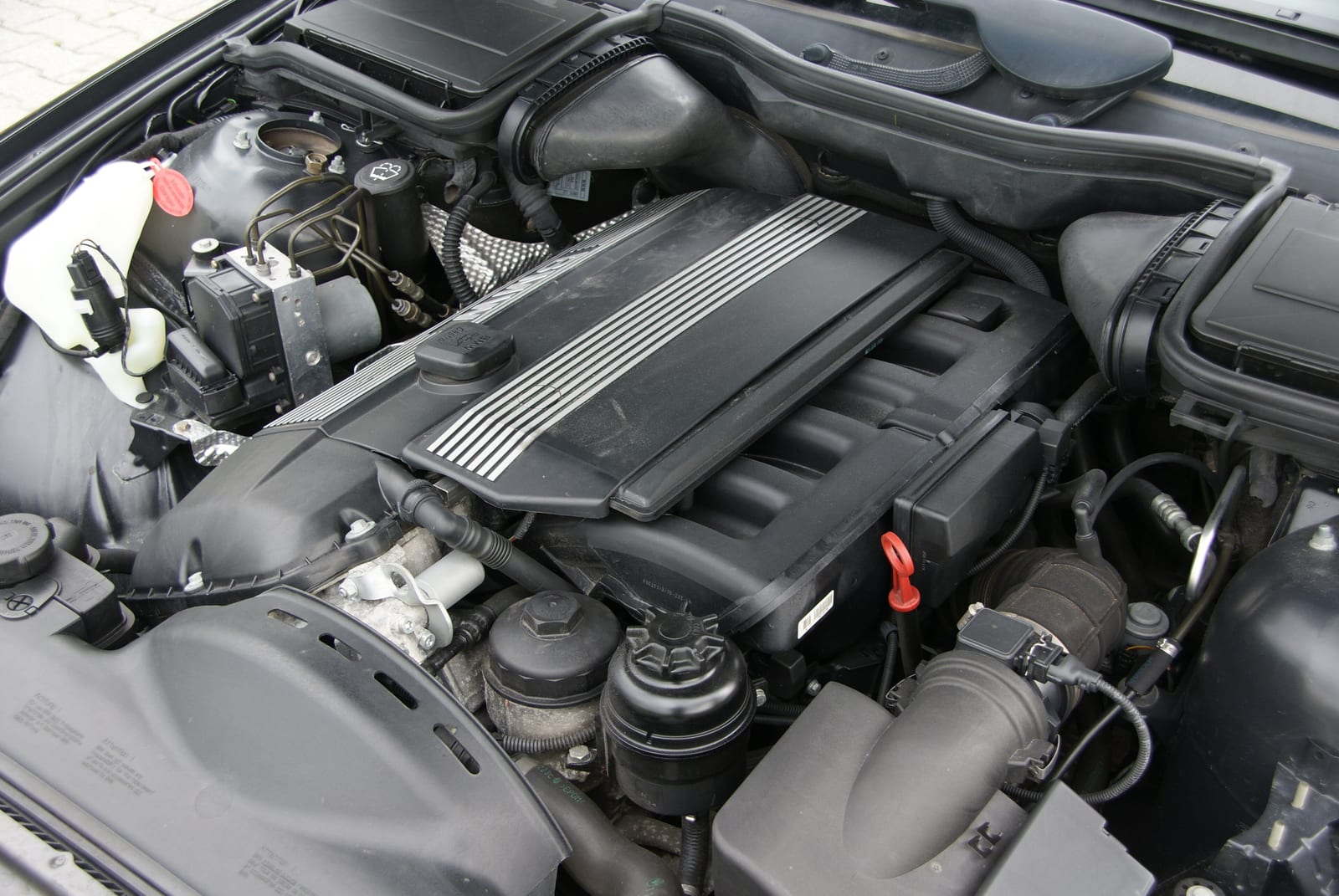 BMW M54B25 inline-six in an E39 525i engine bay, intake side with the oil dipstick